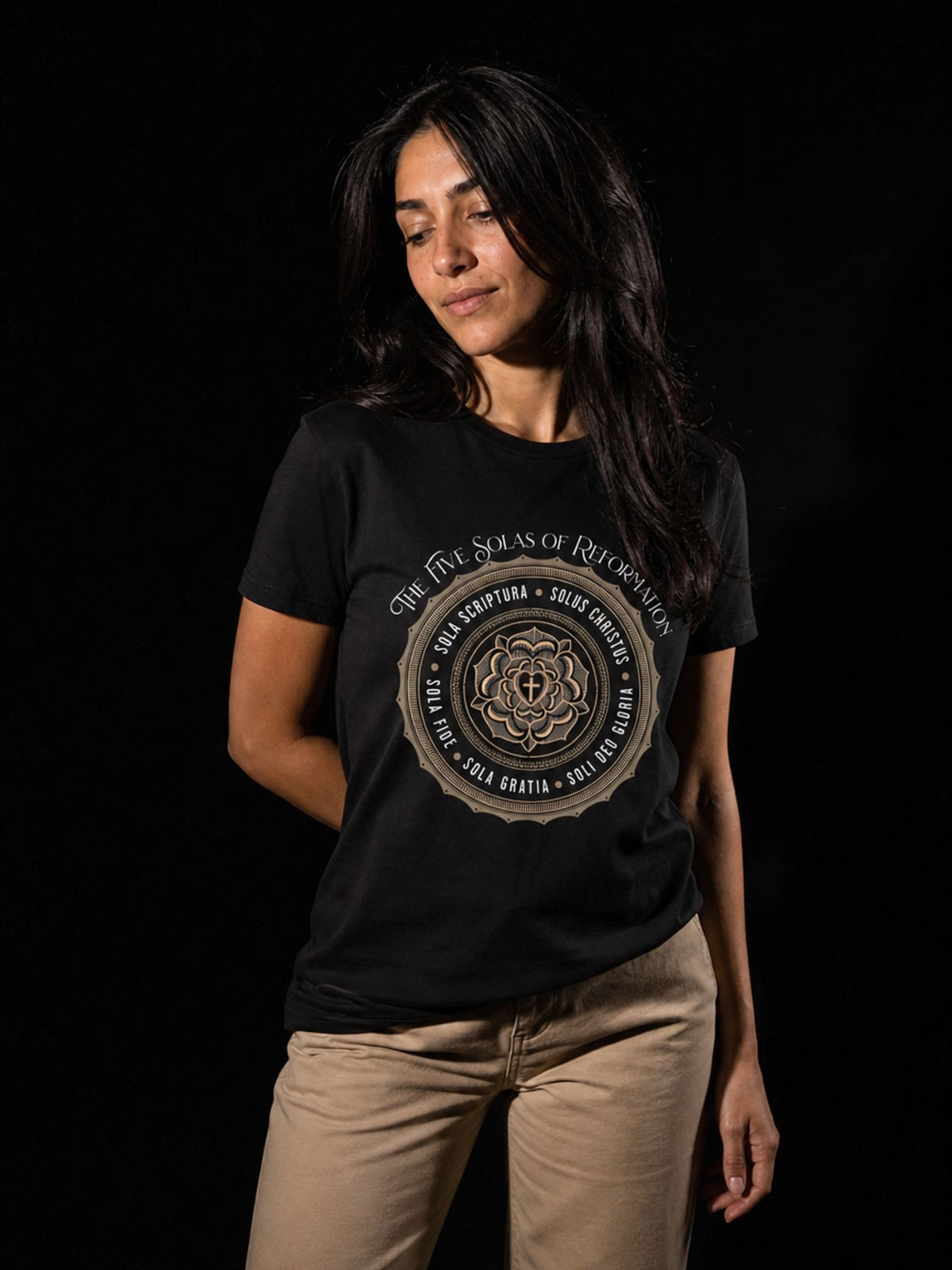 Woman wearing a black Five Solas of the Reformation T-shirt with cream trousers