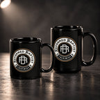 Two black ceramic mugs with a circular 'Reformed Baptist Calvinist' logo, displayed on a dark reflective surface against a dark background.