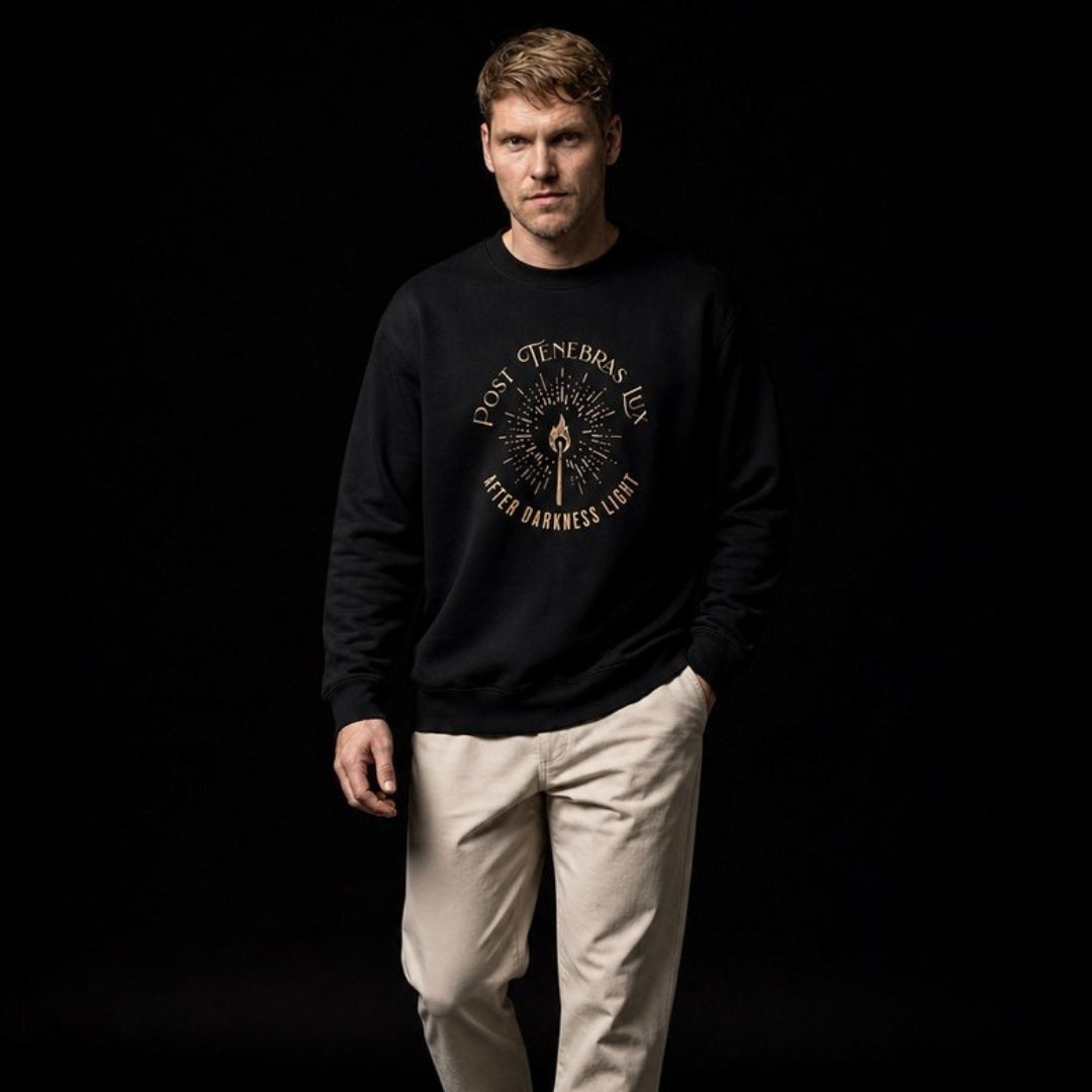 Male model wearing Post Tenebras Lux black crewneck sweatshirt against black studio background