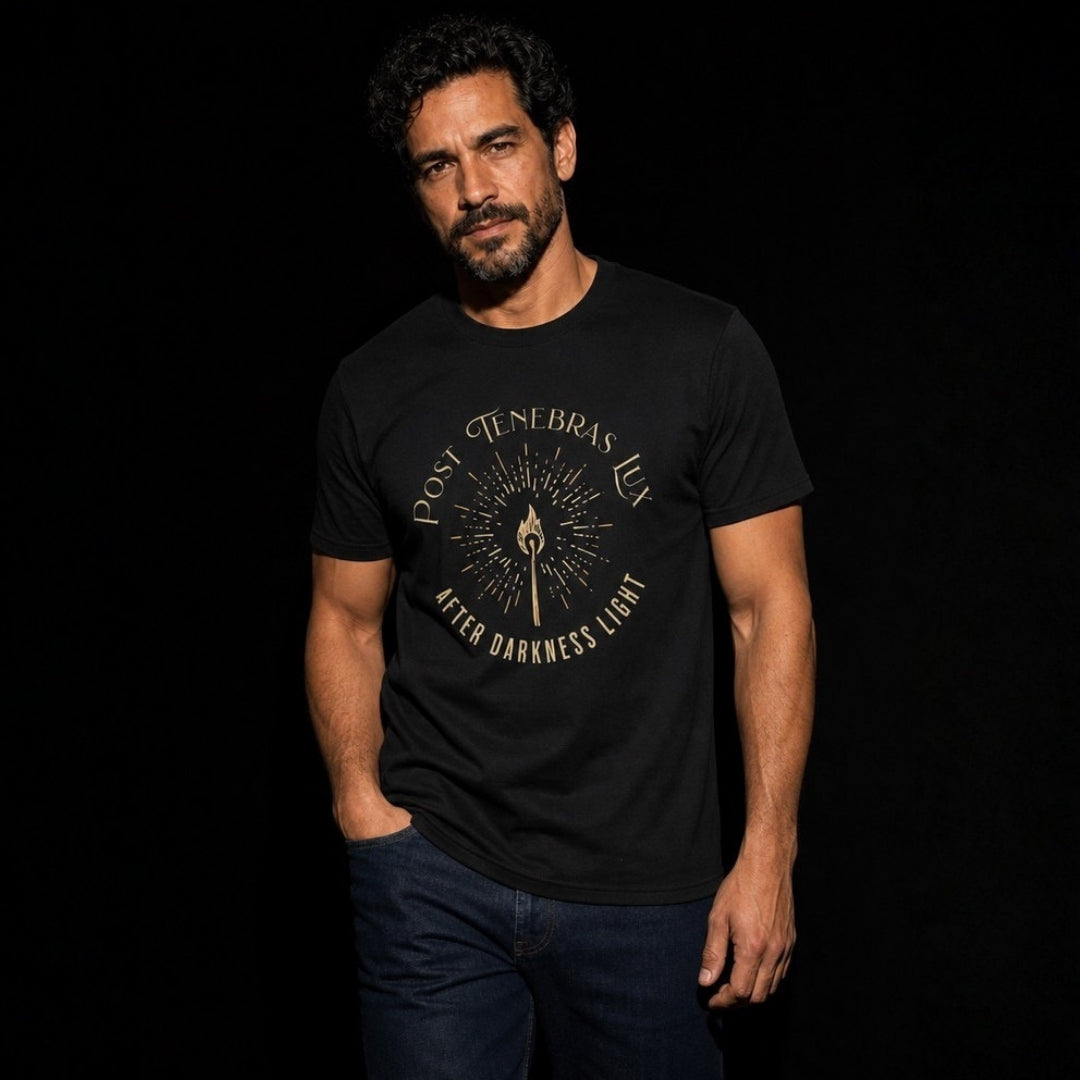 Front view of man wearing black Post Tenebras Lux unisex tee with gold torch design and blue jeans.