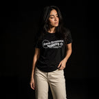 Woman modeling black Semper Reformanda unisex tee with cream pants on dark studio background
