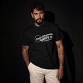 Man modeling black Semper Reformanda unisex tee against dark studio background